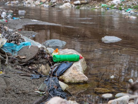 Photo for CLOSE UP: River bank polluted with trashes, plastic waste and debris. Flooded piles of garbage mix and debris on a sandy river shore as ecological issue. Urgent need to raise environmental awareness. - Royalty Free Image