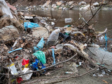 Foto de TIRANA, ALBANIA, MARZO 2022: Inundación de basura plástica en la orilla del río como problema de gestión de residuos. Escombros de río y mezcla de basura de plástico en una orilla del río arenoso. Necesidad de sensibilizar al medio ambiente - Imagen libre de derechos
