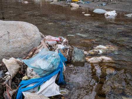 Téléchargez les photos : TIRANA, ALBANIA, MARCH 2022: River shore polluted with piles of garbage, plastic trashes and debris. Flooded garbage at the river bank as ecological issue. The need to raise environmental awareness. - en image libre de droit