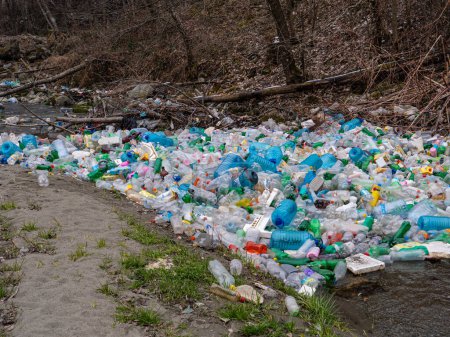 Foto de CLOSE UP: Enormous pile of various plastic bottles floating trapped in a branch. Sad view of polluted river with thrown plastic garbage. Numerous accumulated plastic bottles floating on river surface - Imagen libre de derechos