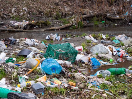 Foto de CLOSE UP: Scattered pile of accumulated various plastic waste on the river bank. Sad view of polluted river bank with plastic garbage. Urgent need to raise environmental awareness. - Imagen libre de derechos