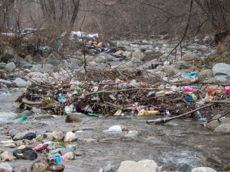Foto de TIRANA, ALBANIA, MARZO 2022: Río fluyendo y sus riberas llenas de una pila de basura plástica. Triste vista del río con desechos plásticos inapropiados que resultan en degradación ambiental. - Imagen libre de derechos