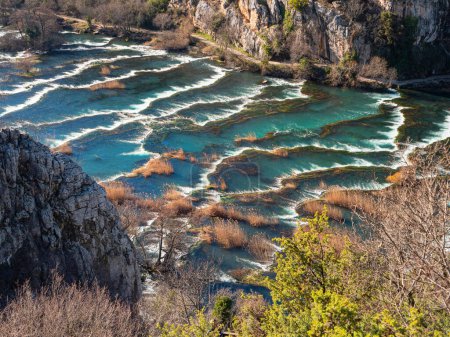 Téléchargez les photos : Scenic view from the cliff with beautiful Krka river flowing over numerous cascades and forming amazing waterscape. Peaceful and picturesque wild natural landmark in protected area open for tourism. - en image libre de droit