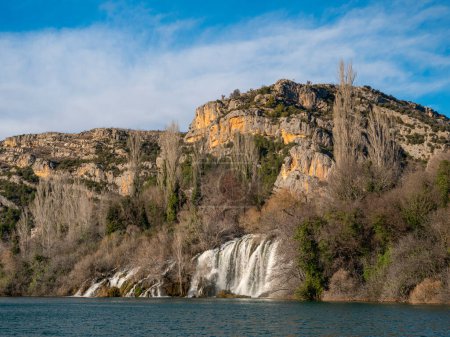 Téléchargez les photos : Amazing waterfall under the limestone cliff joining with beautiful Krka river. Krka river forming amazing waterscape. Peaceful and breathtaking wild nature under environmental conservation program. - en image libre de droit