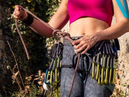 Téléchargez les photos : CLOSE UP: Young female climber making a knot for attaching rope to climbing belt. Preparation of climbing equipment for lead climbing up the rocky wall. Outdoor sport activity in natural environment. - en image libre de droit