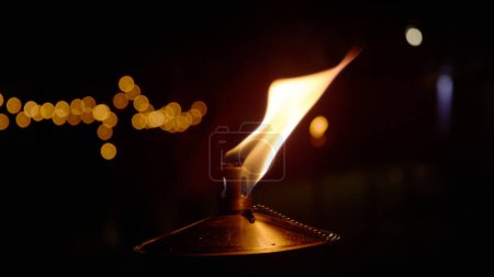 Foto de CLOSE UP: Detailed view of burning flame from metal oil lamp at night time. Orange glowing flame from oil based lamp with black background and bokeh. Mesmerizing ambiance light for evening mood. - Imagen libre de derechos