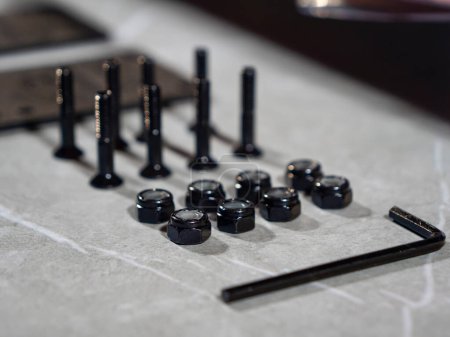 Foto de CLOSE UP: Lined up assortment of nuts, bolts and Allen key on gray countertop. Beautifully organized collection of metal tools on working desk in the workshop. Aligned assembling parts ready to use. - Imagen libre de derechos