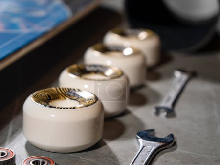 Foto de LA, UNITED STATES, APRIL 2022: CLOSE UP: Overview of lined up skateboard wheels and wrenches on gray countertop. New skateboard elements and other parts arranged on work desk ready for assembling. - Imagen libre de derechos