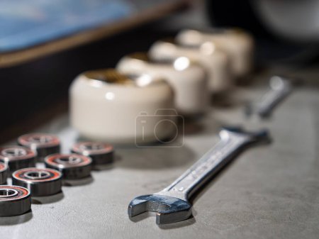 Photo for LA, UNITED STATES, APRIL 2022: CLOSE UP: Wrench lined up with skateboard wheels and bearings on working desk. New skateboard elements and other parts arranged on work desk ready for assembling. - Royalty Free Image