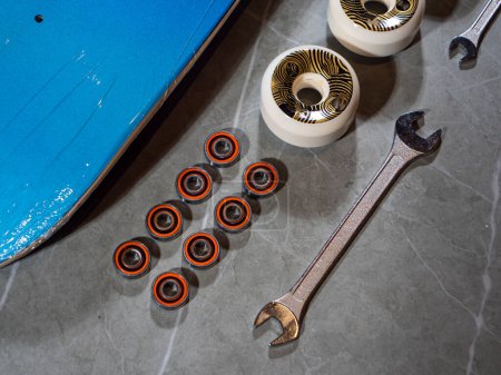 Photo for LA, UNITED STATES, APRIL 2022: TOP DOWN: Close up view of lined up skateboard bearings and wheels with wrench. Ordered sequence of individual skateboard parts and tool on countertop ready for assembly - Royalty Free Image