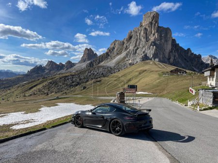 Téléchargez les photos : GIAU PASS, DOLOMITES, ITALY, MAY 2022: Breath-taking scenery in the Dolomites mountain pass with sports car at roadside. Black sports car at side of winding mountain road with gorgeous alpine backdrop - en image libre de droit