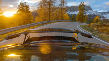 Téléchargez les photos : GIAU PASS, DOLOMITES, ITALY, MAY 2022: Breath-taking scenery while driving the car downhill the mountain road at sunset. Picturesque alpine landscape in the Dolomites bathing in golden sunset light. - en image libre de droit