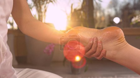 Téléchargez les photos : Sun shinning through massaging hands while performing reflexotherapy. Reflexology therapy for stress ease and helping body work better. Relaxing wellness treatment at the end of the day. - en image libre de droit