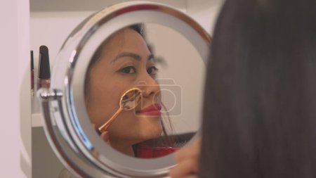Téléchargez les photos : Mirror reflection of beautiful young woman applying contour make up. Pretty lady putting on face blush and make up for special occasion. Female person taking care of her fresh appearance. - en image libre de droit