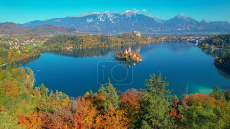 Téléchargez les photos : AÉRIAL Lac de Bled avec toile de fond de montagne et église sur petite île en automne. Charmante destination de voyage de renommée mondiale dans de belles couleurs de la saison d'automne. Une vue incroyable sur les bonbons slovènes pour les yeux - en image libre de droit