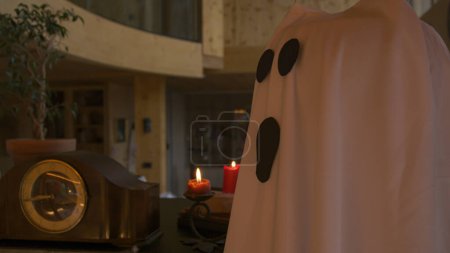 Téléchargez les photos : CLOSE UP: Spooky and mysterious Halloween home decor for setting festive ambience. Detailed view of mystical home decorations with ghost, candles, cobwebs and old clock for traditional October holiday - en image libre de droit