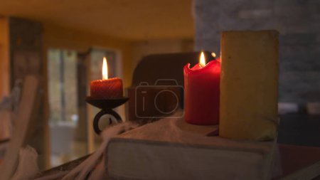 Photo for CLOSE UP: Red burning candles and old books covered in cobwebs for Halloween mood. Detailed view of mystical and spooky home interior decorations for celebrating traditional autumn holiday in October. - Royalty Free Image