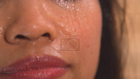 Foto de Sweat drops dripping down the beautiful face of a young woman in sauna. Detailed view of lady's face sweating in Finnish sauna for detoxification and strengthening of the immune system. - Imagen libre de derechos