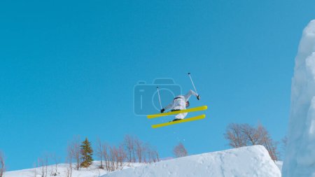 Téléchargez les photos : Young freestyle skier jumping big air in snow park at ski resort. Athlete performs spin trick at snowy ski area. Extreme winter action full of adrenaline in snow-covered mountains. - en image libre de droit