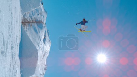 Téléchargez les photos : Young male extreme athlete in action at snow park in ski resort. Freestyle skier flying through air after jumping big air. Winter adrenaline action in snow-covered alpine mountains. - en image libre de droit