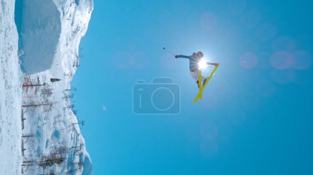 Téléchargez les photos : Extreme skier performs grab trick while jumping big air kicker. Young male athlete in action at snowy snow park in ski resort. Adrenaline activity on sunny winter day in ski area. - en image libre de droit
