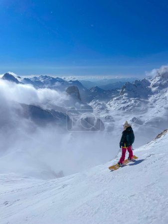 Photo for Female freerider with strapped snowboard before descending on fresh powder snow. Breath-taking views in pristine Albanian Alps and endless possibilities for snowboarding untracked mountain terrains. - Royalty Free Image