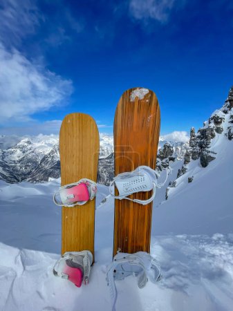 Téléchargez les photos : Two snowboards stuck in pile of snow on top of freeride line with fresh snowpack. Female and male snowboard setup in full readiness for riding powder snow on untouched and pristine mountain terrains. - en image libre de droit