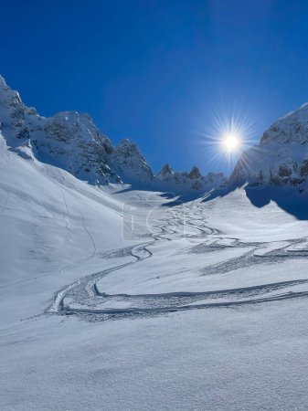 Foto de Fresh winding tracks of freeride skiers and snowboarders in deep powder snow. Beautiful travel destination for adventurous heliboarding and heliskiing in pristine and snow-covered Albanian Alps. - Imagen libre de derechos