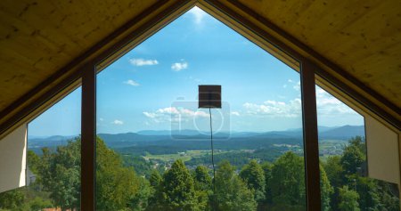 Téléchargez les photos : Robotic window cleaner washing glass windows with gorgeous countryside backdrop. Intelligent home appliance for washing hard-to-reach windows. Convenient electronic device for futuristic housekeeping. - en image libre de droit