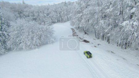 Foto de LJUBLJANA, SLOVENIA - MARCH 2022: Off-road adventure ride with Suzuki Jimny through snow-covered forest. Mini 4-wheel SUV vehicle moving through woodland along snow-covered road on cloudy day. - Imagen libre de derechos