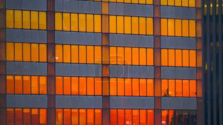 Foto de CERRAR: El cielo anaranjado quemado de la mañana se refleja en las ventanas de los rascacielos modernos del distrito financiero de Nueva York. Edificio corporativo remolcado está iluminado por el impresionante atardecer dorado. - Imagen libre de derechos
