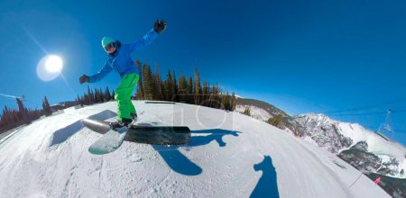 Photo for CLOSE UP, LENS FLARE: Freestyle snowboarder slides along a metal rail in the fun park of a ski resort in Colorado. Cool action shot of a freeride snowboarder sliding down a rail on a perfect sunny day - Royalty Free Image