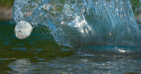 Photo for MACRO, DOF: Cinematic close up shot of a flat pebble bouncing off the shimmering surface of a calm mountain stream. Small flat stone recoils off a shallow river. Crystal clear water splashing wildly - Royalty Free Image