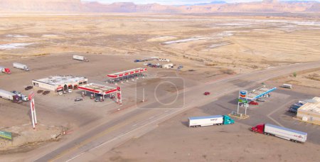 Foto de UTAH, ESTADOS UNIDOS DE AMÉRICA, MARZO 2019: AERIAL: Volando por encima de las gasolineras ConocoPhillips y Chevron en el escarpado desierto de Utah. Camioneros y viajeros se detienen en una estación de descanso comercial. - Imagen libre de derechos