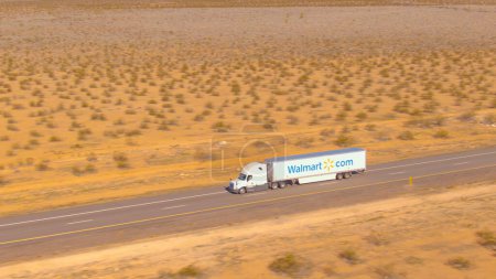 Photo for UTAH, UNITED STATES OF AMERICA, MARCH 2019: AERIAL: Flying along a Walmart truck hauling a cargo container across the Utah desert. Walmart freight truck drives along an empty interstate freeway. - Royalty Free Image