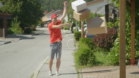 Photo for Lazy young delivery guy throws packages in someone's driveway on a sunny day. - Royalty Free Image