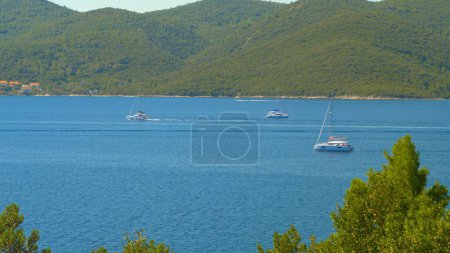 Photo for Tourist sailboats sail around the tranquil Adriatic sea on a sunny summer day. - Royalty Free Image