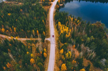 Photo for Aerial view of road with car through fall woods with green and yellow trees in Finland. Beautiful autumn landscape. - Royalty Free Image
