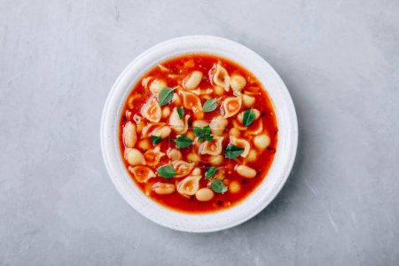 Photo for Tomato soup. Minestrone soup. Tomato bean and pasta soup bowl on gray stone background. Top view, copy space. - Royalty Free Image