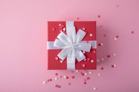 Photo for Gift box for Valentine's day. Red gift present box with heart confetti on pink background, top view with copy space. - Royalty Free Image