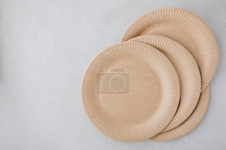 Photo for Disposable paper tableware paper plates on gray stone background, top view, copy space. Plastic free and zero waste concept. - Royalty Free Image
