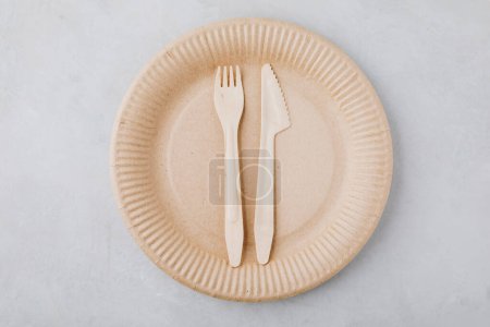 Photo for Disposable paper tableware (paper plates, wooden forks, knives, ) on gray stone background, top view, copy space. Plastic free and zero waste concept. - Royalty Free Image