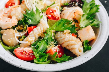 Photo for Seafood salad bowl. Green lettuce tomato salad with shrimps, scallop and squids on dark background - Royalty Free Image
