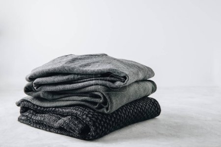 Photo for Sweaters. Black knitted sweaters stacked on gray background. - Royalty Free Image
