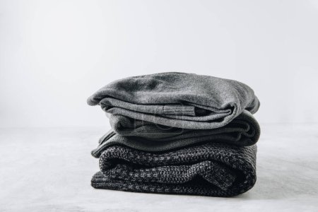 Photo for Sweaters. Black knitted sweaters stacked on gray background. - Royalty Free Image