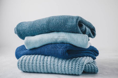 Photo for Sweaters. Blue knitted sweaters stacked on gray background. - Royalty Free Image