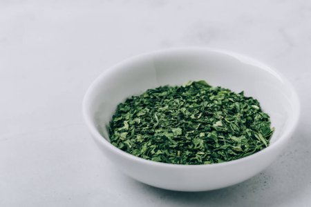 Photo for Parsley. Dried herb parsley green leaves in bowl on gray background - Royalty Free Image