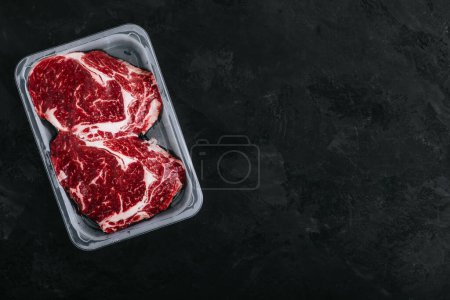 Photo for Ground Beef steak in vacuum packaging on dark stone background, top view, copy space - Royalty Free Image