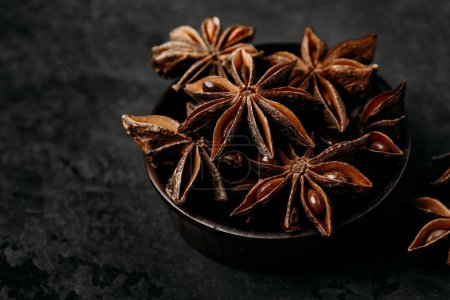 Photo for Anise. Star anise in a wooden bowl dark stone background, close-up - Royalty Free Image
