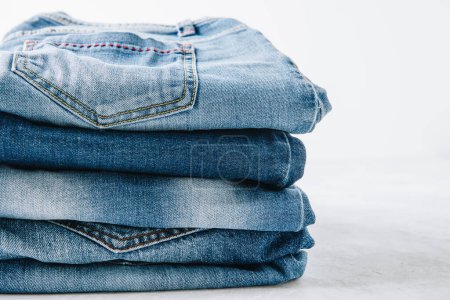 Photo for Jeans. Blue jeans trousers stack on light stone background, copy space. - Royalty Free Image